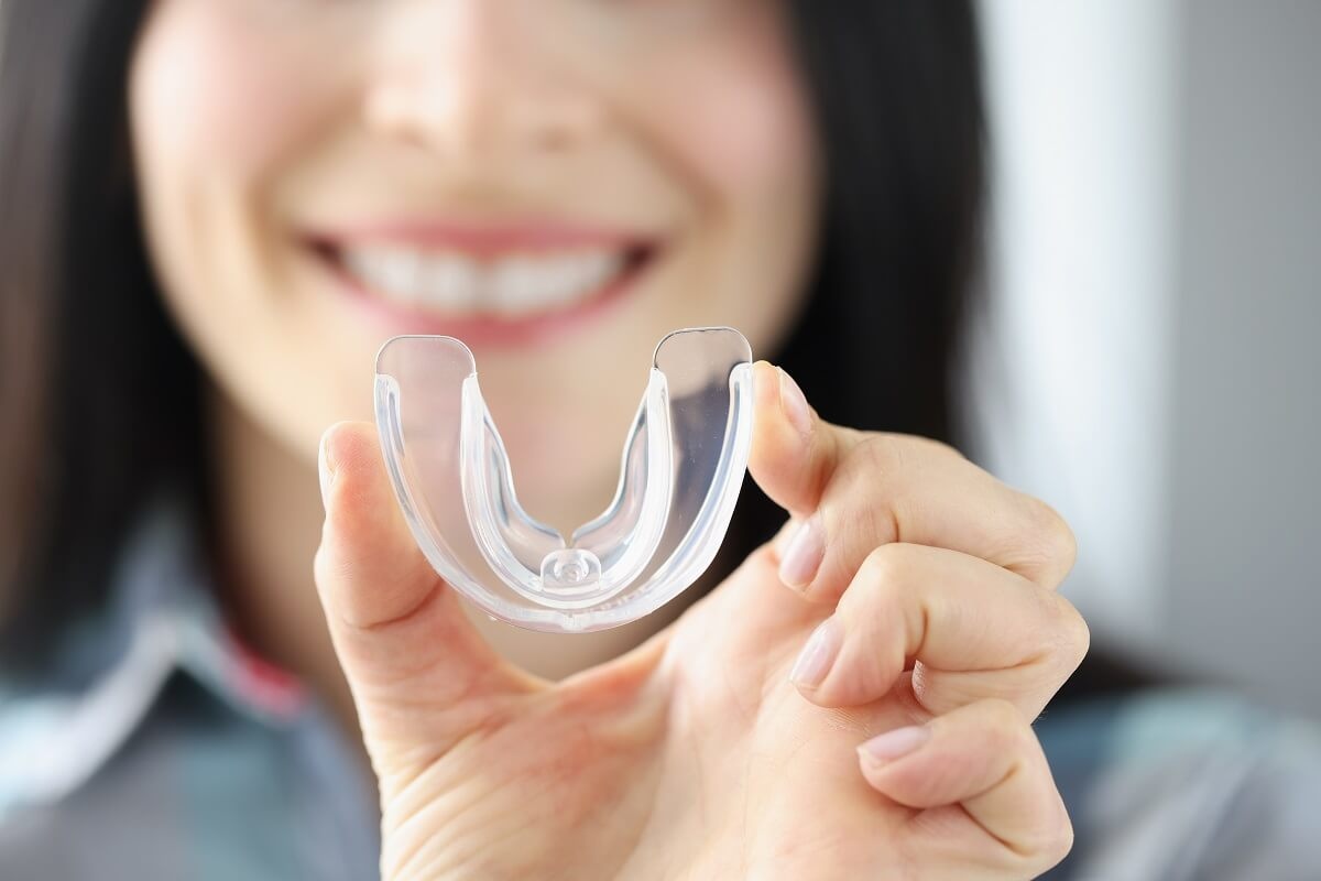 Custom mouthguard held in front of a smiling patient