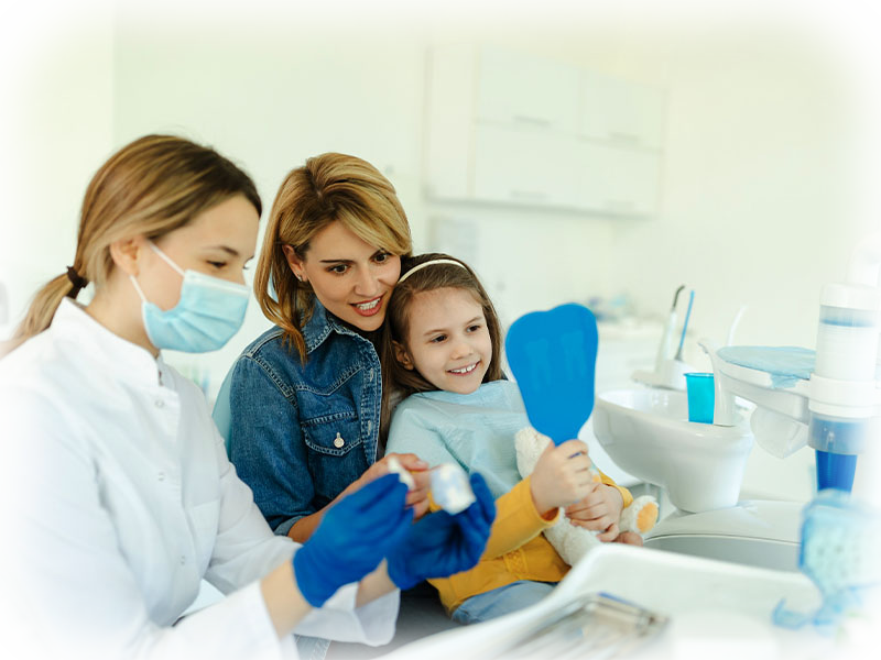 Child smiling with mother and dentist during a children's dentistry visit