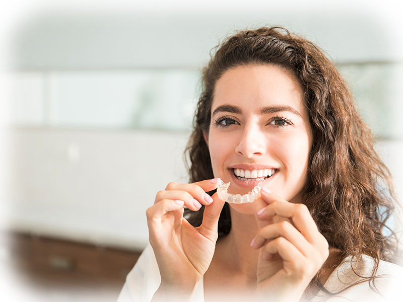 Patient holding clear Invisalign retainers in a modern dental office